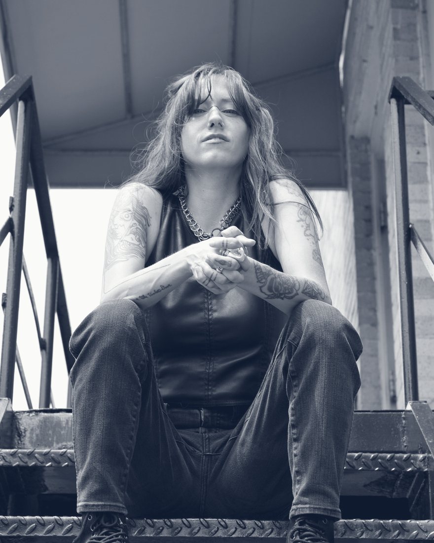 Bridgette Kidd sitting on a metal fire escape stair, looking down at the camera