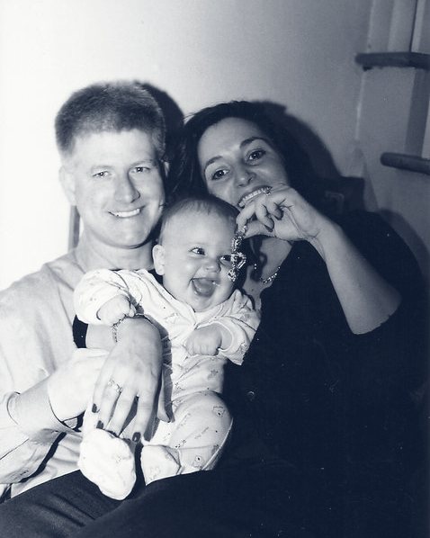 Anthony Schilt as a baby, laughing, held by his parents