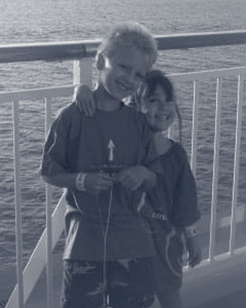 Anthony and his sister Kristina as young kids at a railing by the water